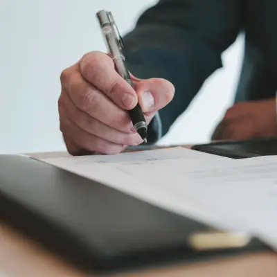 A man's hand holding a pen over a sheet of paper